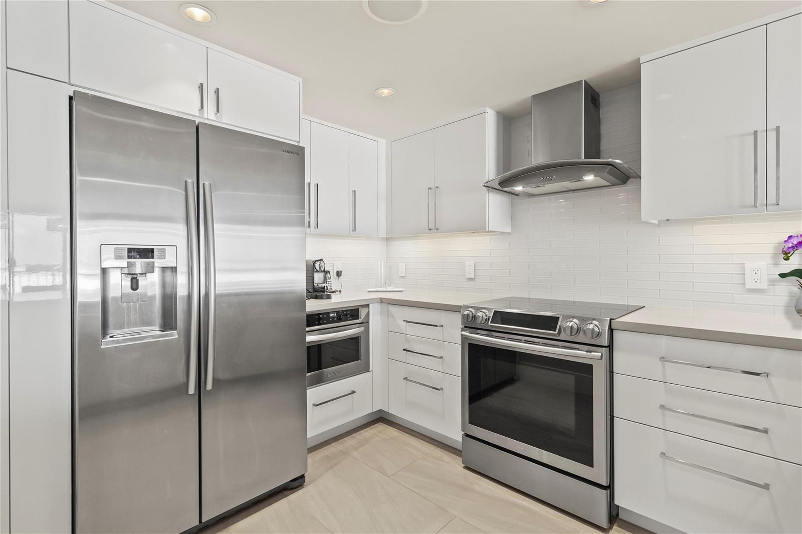 A modern kitchen features white cabinets, stainless steel appliances, and a white subway tile backsplash — 800 SE 20th Avenue # 809, Deerfield Beach FL 33441, DEERFIELD BEACH, FL