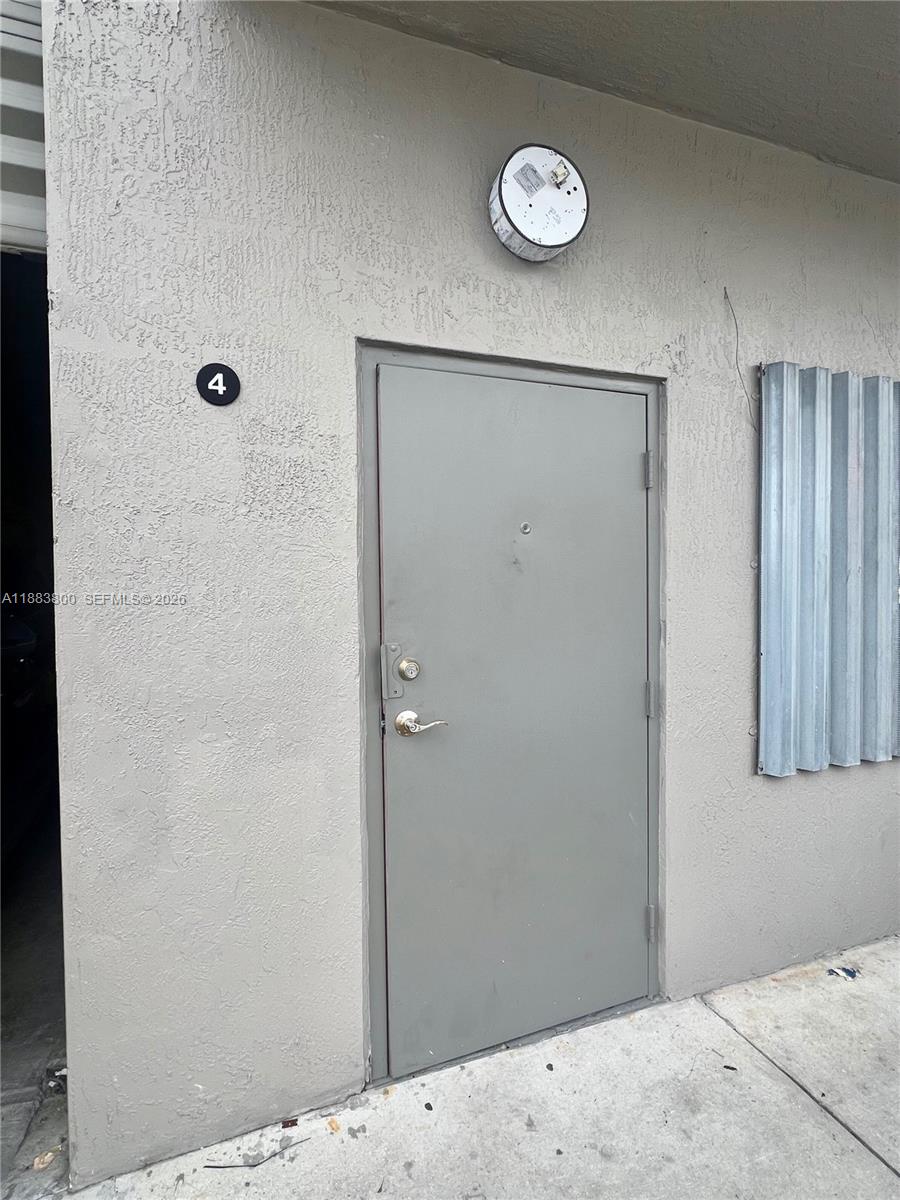A gray exterior door marked with the number four is set into a stucco wall — 16215 SW 117th Ave # 4, Miami FL 33177, MIAMI, FL