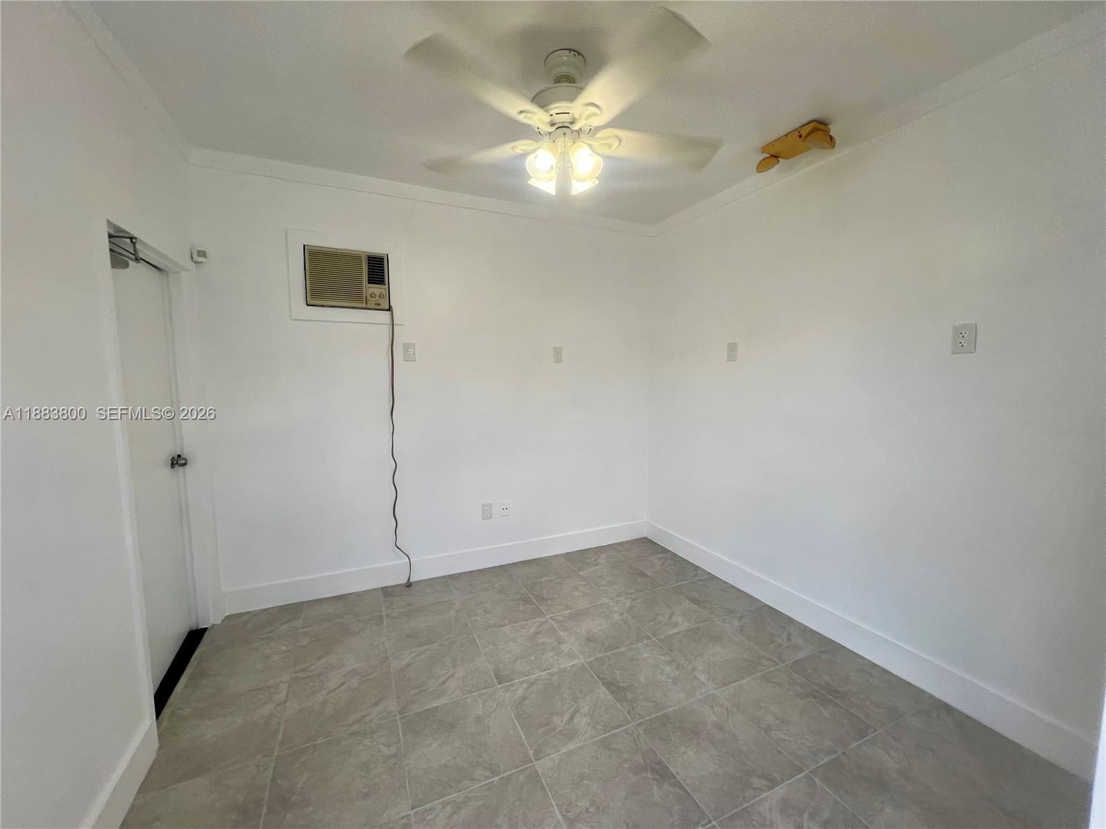 An empty room features white walls, tile flooring, a ceiling fan, and a window air conditioner — 16215 SW 117th Ave # 4, Miami FL 33177, MIAMI, FL
