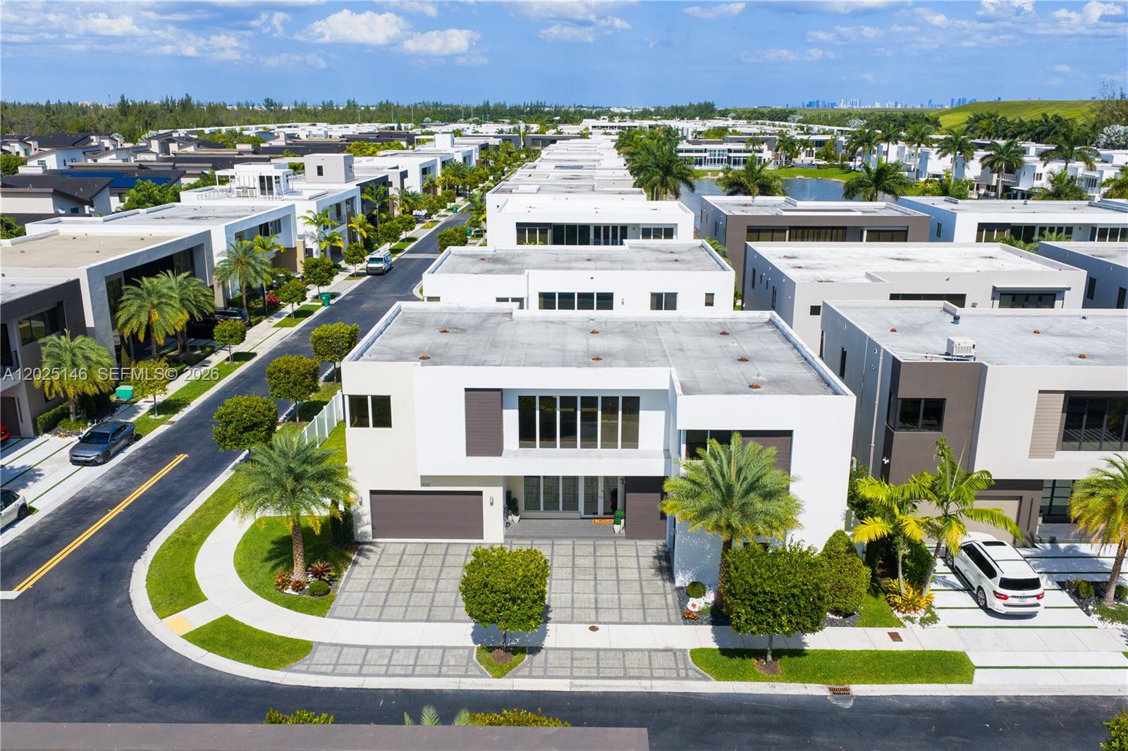 An aerial view shows a modern white two-story house with a paved driveway and palm trees — 7525 NW 103rd Pl, Doral FL 33178, DORAL, FL