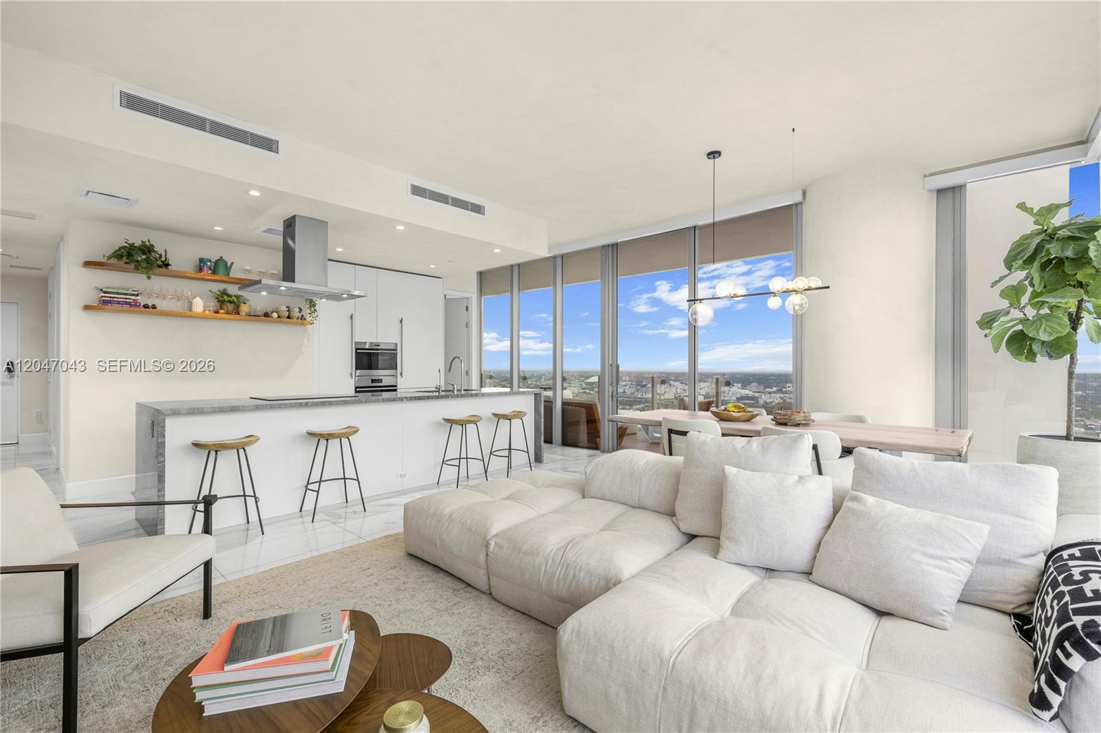 A modern open-concept living area features a kitchen with bar seating and floor-to-ceiling windows — 700 NE 26th Ter # 5006, Miami FL 33137, MIAMI, FL