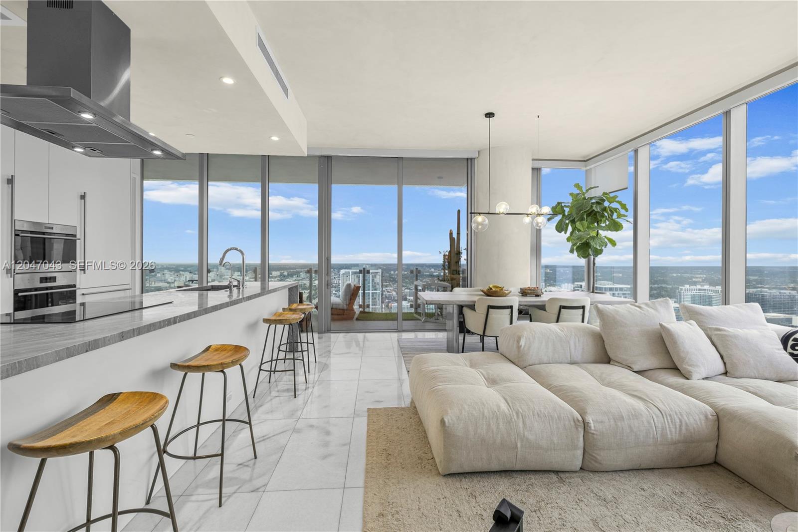 A modern open-concept living area features a kitchen with bar seating and floor-to-ceiling windows — 700 NE 26th Ter # 5006, Miami FL 33137, MIAMI, FL