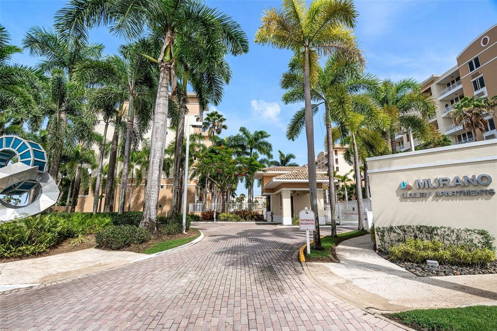 The entrance to the Murano Luxury Apartments features a brick driveway, palm trees, and signage — 1 PALMA REAL AVE. UNIT 2 A6, GUAYNABO, PR
