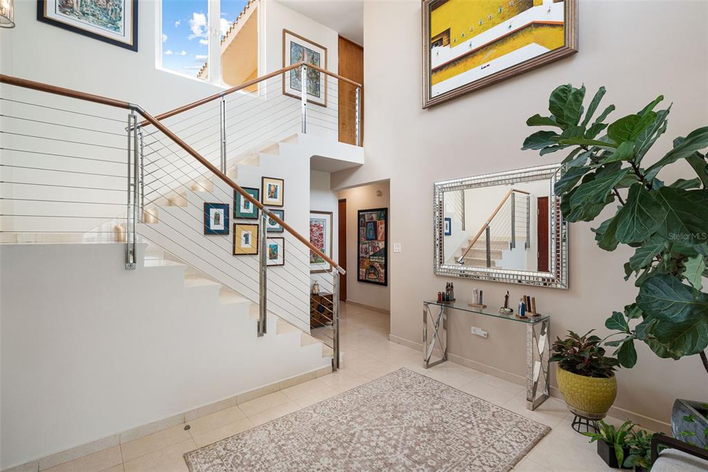 A bright entryway features a staircase with cable railings, a large mirror, and tiled floors — 1 PALMA REAL AVE. UNIT 2 A6, GUAYNABO, PR