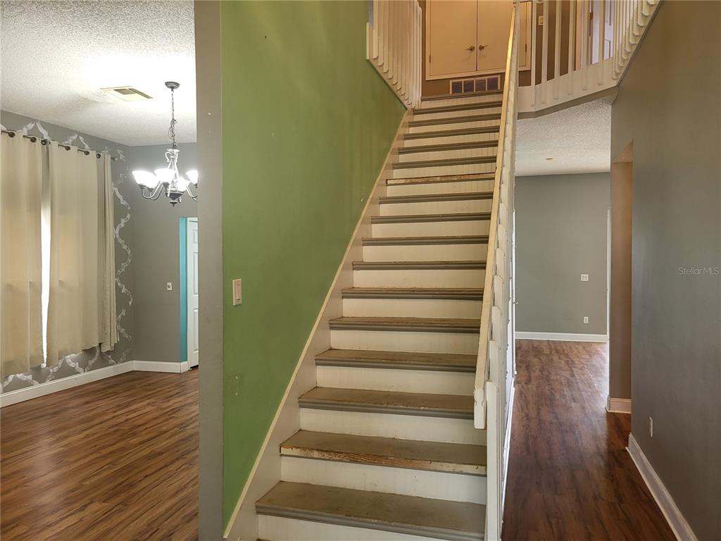 An open-concept living area features wood-look flooring, a teal kitchen island, and white cabinetry — 1188 FOXFORREST CIRCLE, APOPKA, FL