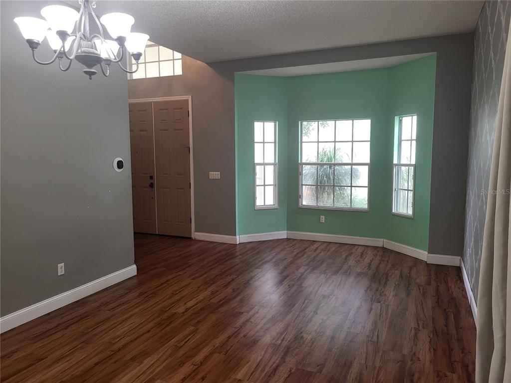 A kitchen with tiled countertops and white cabinets overlooks a living area with built-in shelves — 1188 FOXFORREST CIRCLE, APOPKA, FL