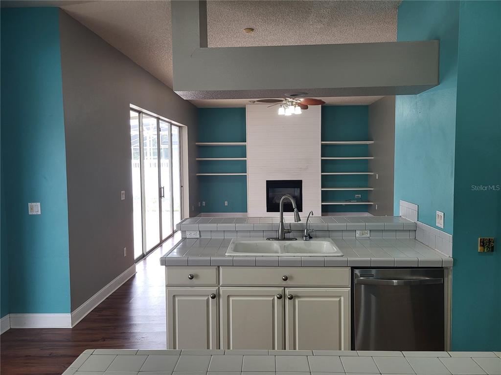 A living room features wood-look flooring, a white fireplace, built-in shelves, and teal accent walls — 1188 FOXFORREST CIRCLE, APOPKA, FL