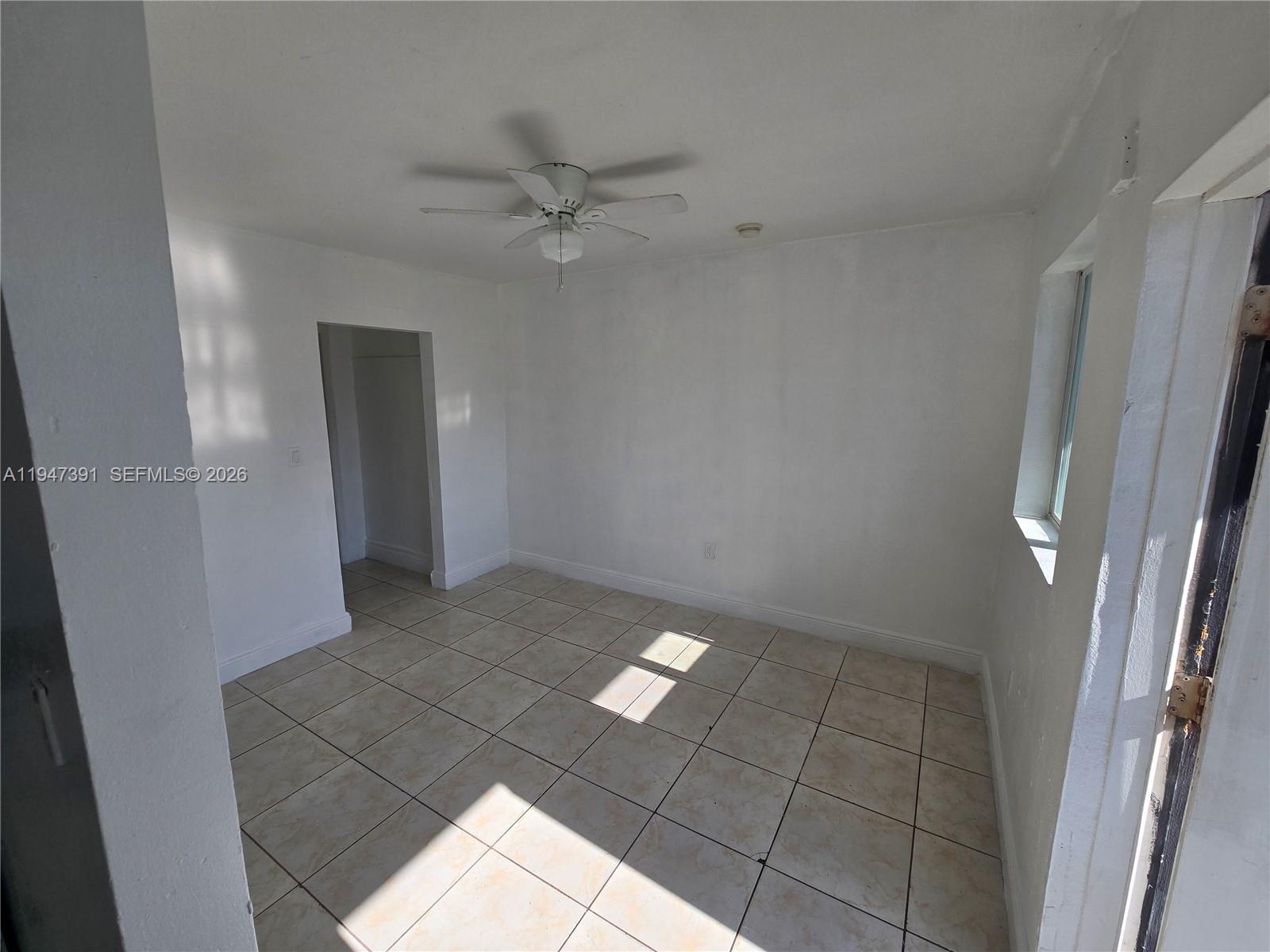 An empty room features white walls, light-colored tile flooring, and a ceiling fan — 535 NW 7th St # 10, Miami FL 33136, MIAMI, FL