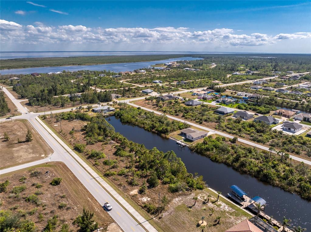 An aerial view shows a canal-front residential neighborhood with houses, vacant lots, and a road — 15125 INGRAHAM BOULEVARD, PORT CHARLOTTE, FL