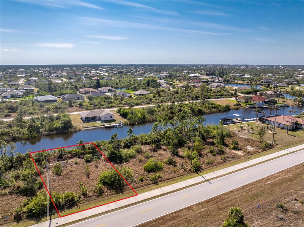 An aerial view shows a vacant, rectangular lot bordered by a road and a canal — 15125 INGRAHAM BOULEVARD, PORT CHARLOTTE, FL
