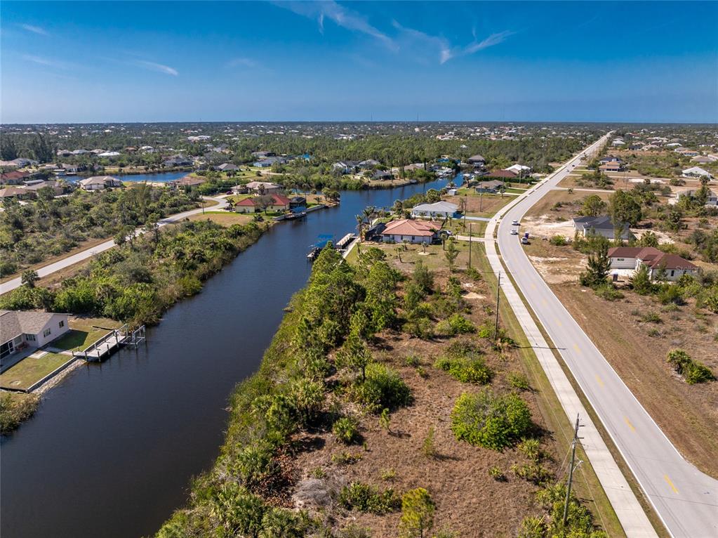 An aerial view shows a canal running alongside a road with several houses nearby — 15125 INGRAHAM BOULEVARD, PORT CHARLOTTE, FL