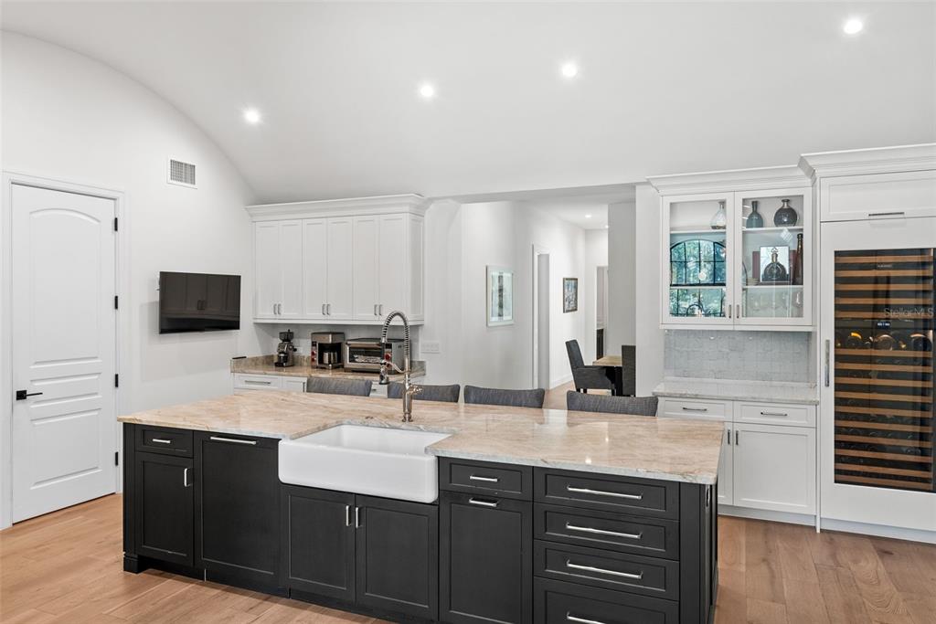 A kitchen features a large dark island with a farmhouse sink and white perimeter cabinetry — 18907 LAKES EDGE WAY, ODESSA, FL