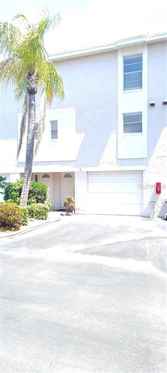 A multi-story townhouse exterior features a palm tree, a white garage door, and two windows — 255 CAPRI CIRCLE N UNIT 36, TREASURE ISLAND, FL