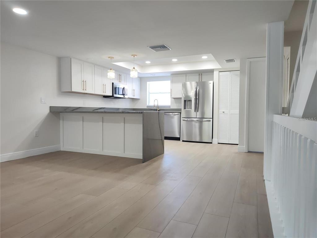 A modern kitchen features white cabinets, stainless steel appliances, and a gray waterfall island — 255 CAPRI CIRCLE N UNIT 36, TREASURE ISLAND, FL