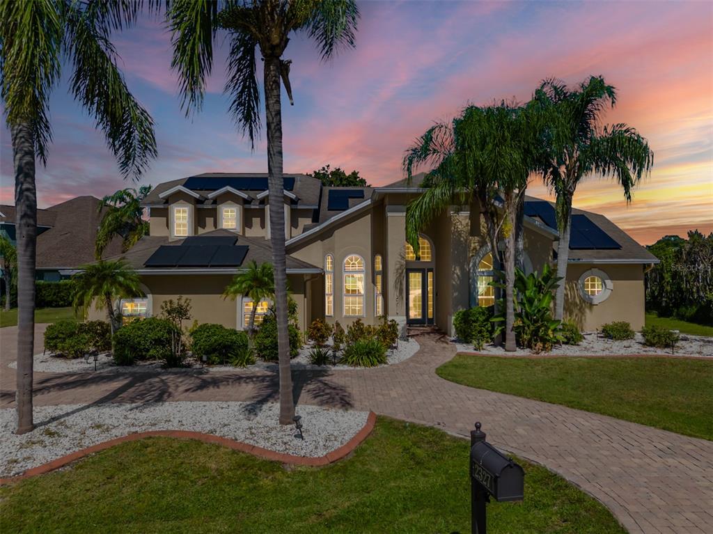 A two-story house with solar panels on the roof and a paved walkway at dusk — 2327 CAMP INDIANHEAD ROAD, LAND O LAKES, FL