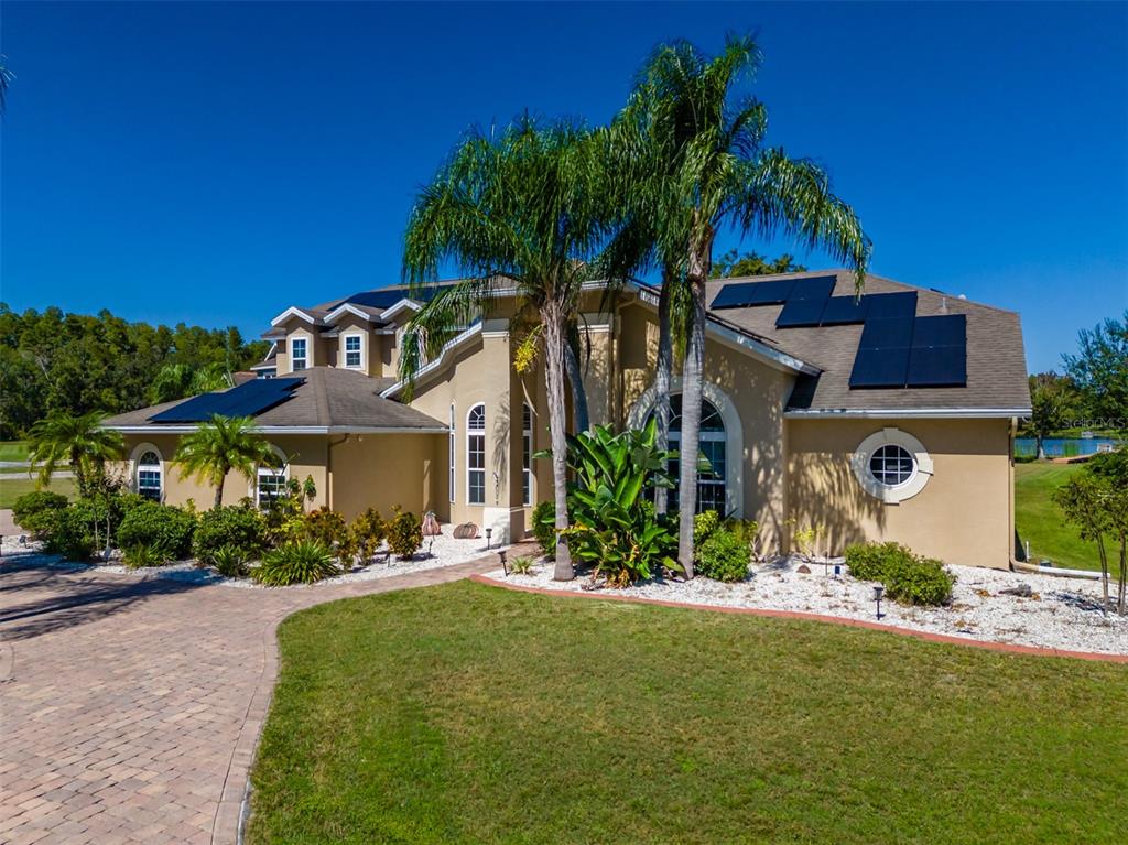 A tan two-story house with solar panels on the roof and a paved driveway — 2327 CAMP INDIANHEAD ROAD, LAND O LAKES, FL