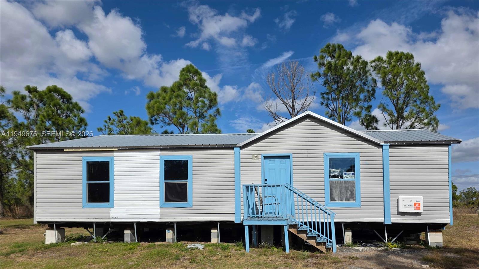 A single-story manufactured home with grey siding, blue trim, and a metal roof — 8357 Strasse Blvd, Punta Gorda FL 33982, PUNTA GORDA, FL
