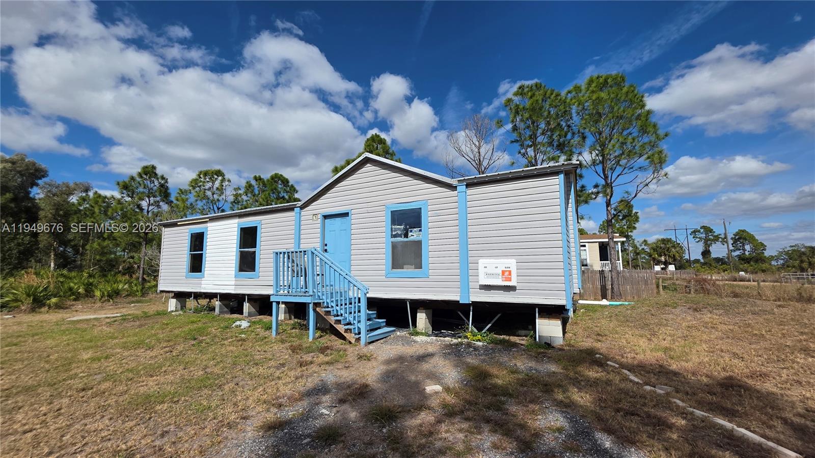 A single-story manufactured home with light gray siding and blue trim sits on a grassy lot — 8357 Strasse Blvd, Punta Gorda FL 33982, PUNTA GORDA, FL