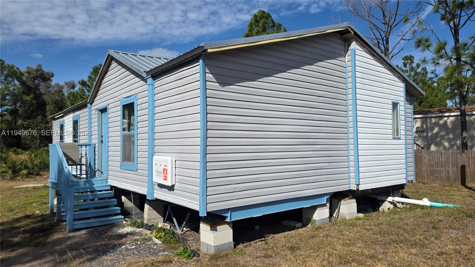 The exterior of a light gray manufactured home features blue trim and a metal roof — 8357 Strasse Blvd, Punta Gorda FL 33982, PUNTA GORDA, FL
