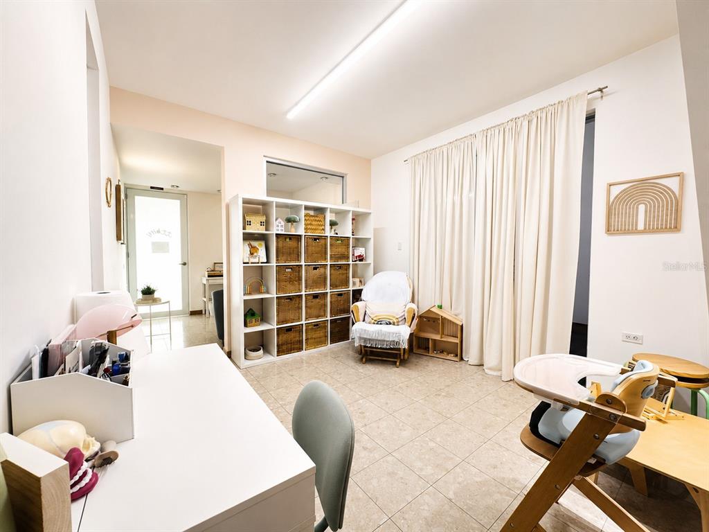 A room with tile flooring, a white shelving unit, a rocking chair, and a high chair — ACERINA #7 URB. MUÑOZ RIVERA (AVE. MARTINEZ NADAL) UNIT LOCAL A, GUAYNABO, PR