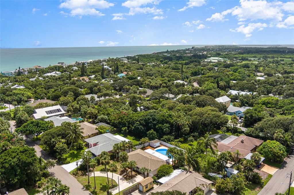 An aerial view shows a residential neighborhood with lush trees and a nearby coastline — 125 MATANZAS ROAD, MELBOURNE BEACH, FL