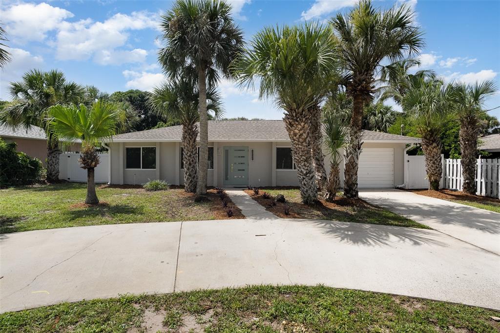 A single-story house with a light-colored exterior, a teal front door, and several palm trees — 125 MATANZAS ROAD, MELBOURNE BEACH, FL