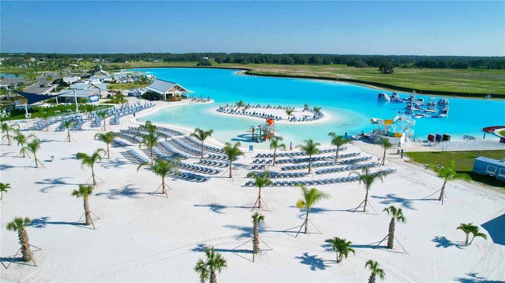 An aerial view shows a large turquoise lagoon with a sandy beach and palm trees — 31665 OCEAN BREEZE DRIVE, SAN ANTONIO, FL