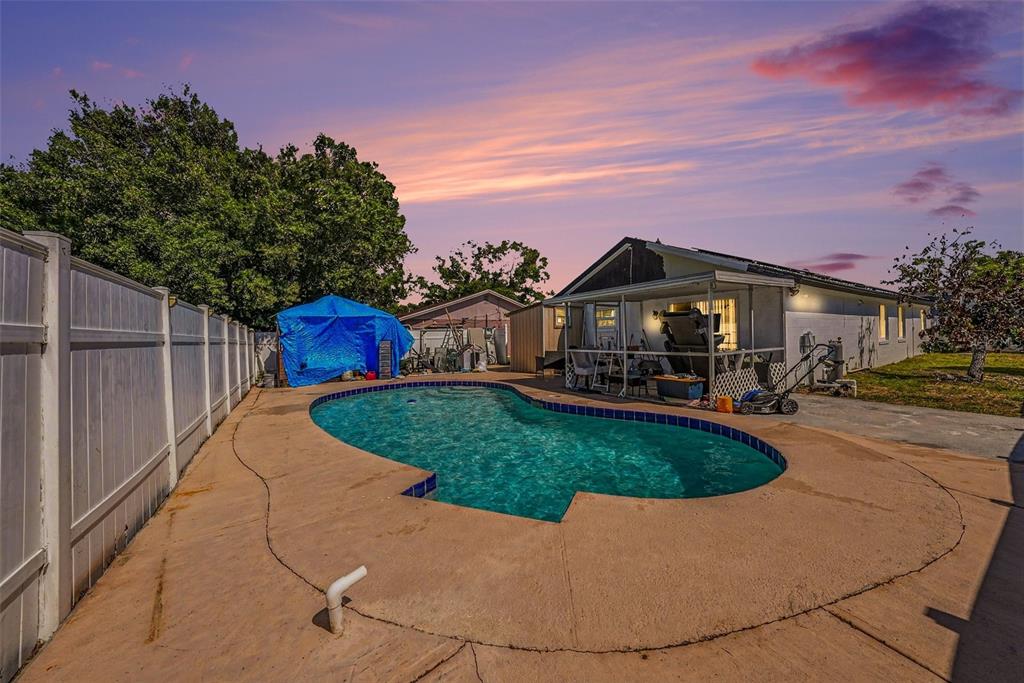 A backyard features a swimming pool, a covered patio, and a white privacy fence — 10119 CHIMNEY HILL COURT, TAMPA, FL