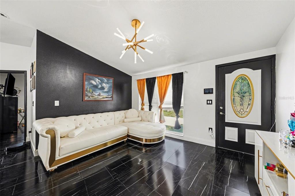 A living room features a white sectional sofa, black marble-look flooring, and a gold chandelier — 10119 CHIMNEY HILL COURT, TAMPA, FL