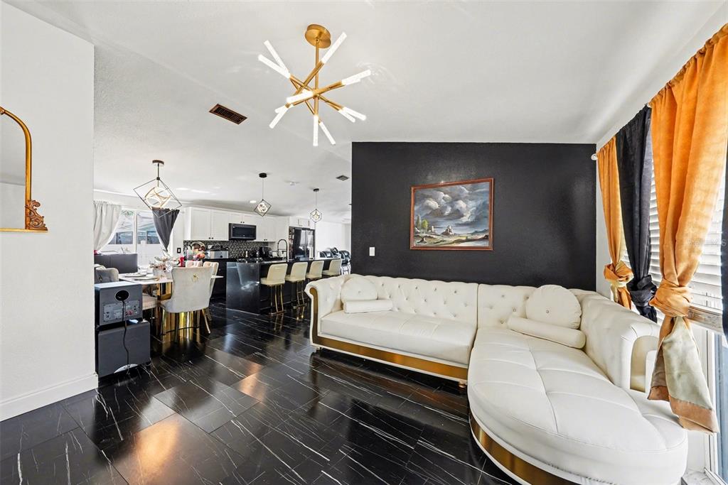 A living room features a white tufted sectional, black accent wall, and black marble flooring — 10119 CHIMNEY HILL COURT, TAMPA, FL