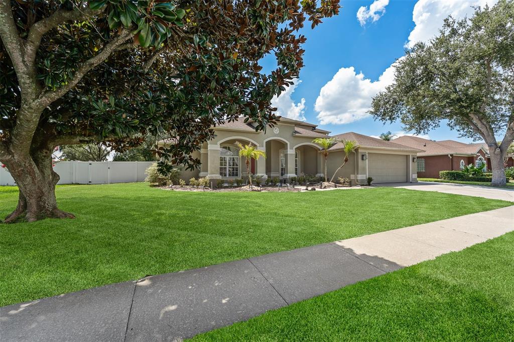 A single-story house with a beige exterior, a two-car garage, and a large front lawn — 718 LITTLE HAMPTON LANE, GOTHA, FL