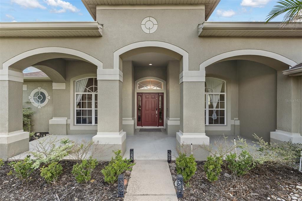 A front exterior view of a house featuring a covered porch and red front door — 718 LITTLE HAMPTON LANE, GOTHA, FL