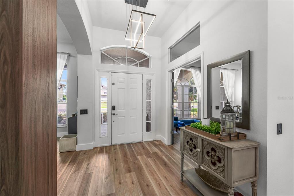 A bright entryway features wood-look flooring, a white front door, and a decorative console table — 718 LITTLE HAMPTON LANE, GOTHA, FL