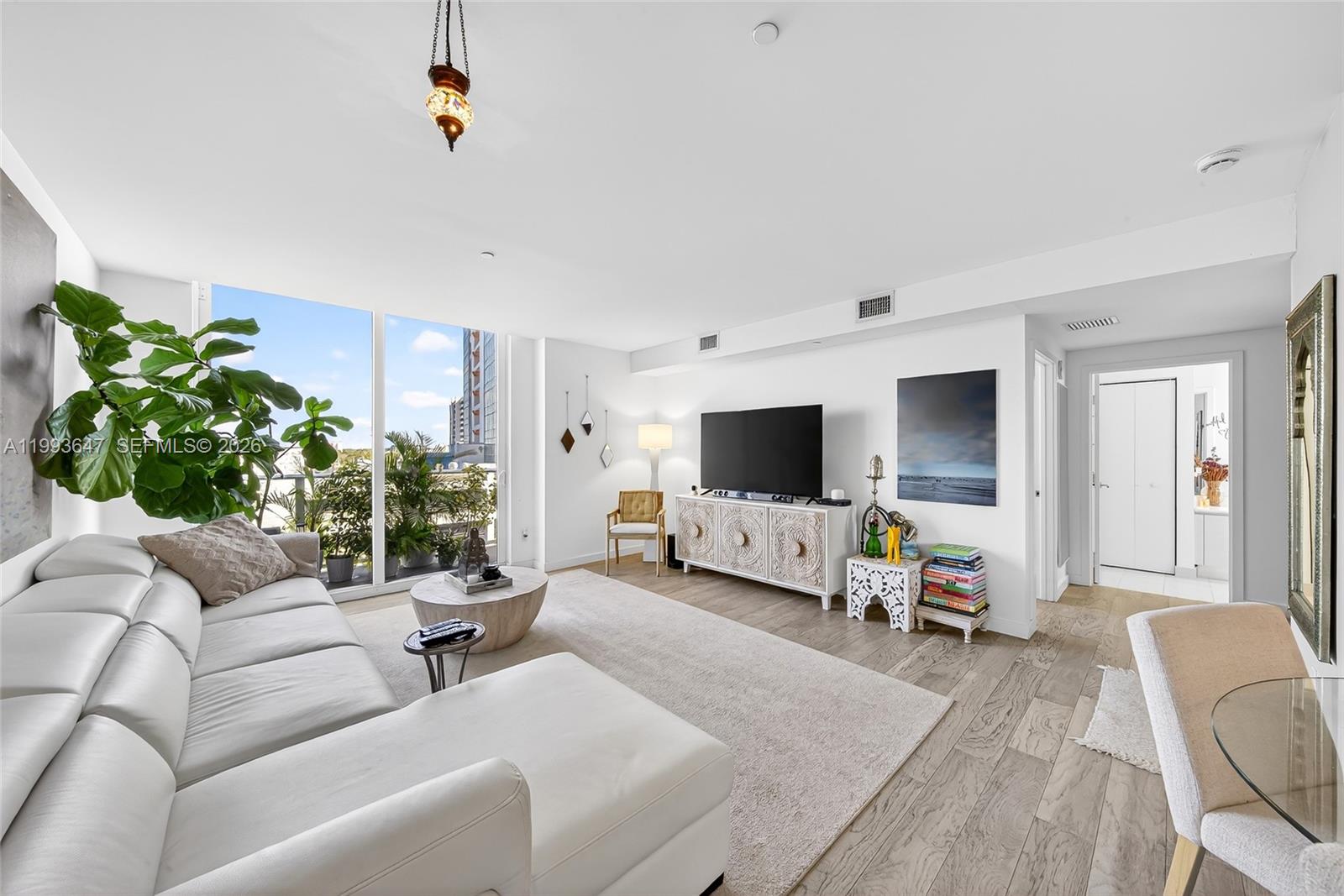 A bright living room features a white sectional sofa, wood flooring, and floor-to-ceiling windows — 4250 Biscayne Blvd # 609, Miami FL 33137, MIAMI, FL