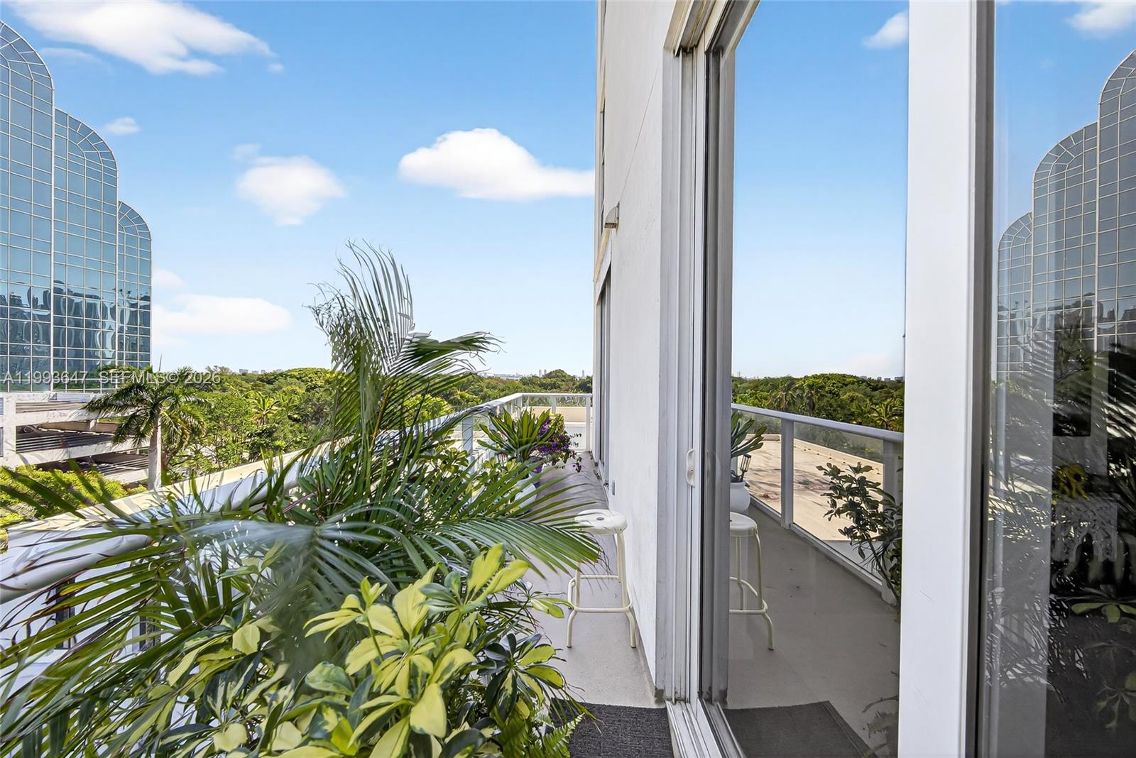 A balcony with potted plants and a white stool overlooks a lush green landscape — 4250 Biscayne Blvd # 609, Miami FL 33137, MIAMI, FL