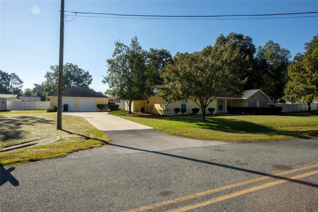 A yellow single-story house with a detached two-car garage and a paved driveway — 618 SE 44TH STREET, KEYSTONE HEIGHTS, FL