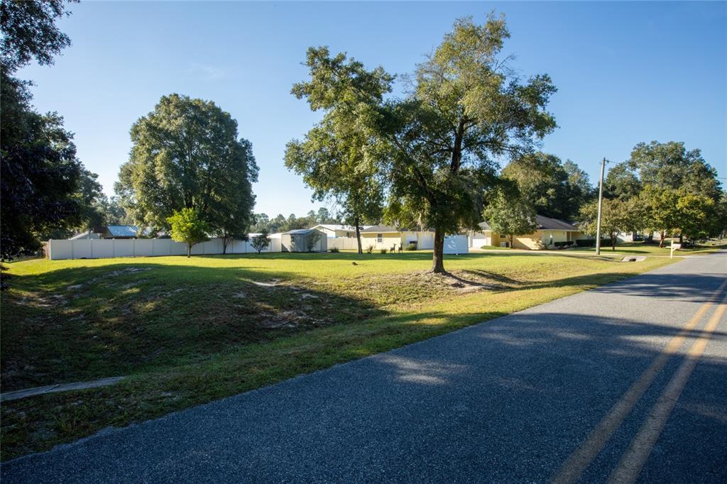 A grassy lot with several large trees sits next to a paved road — 618 SE 44TH STREET, KEYSTONE HEIGHTS, FL