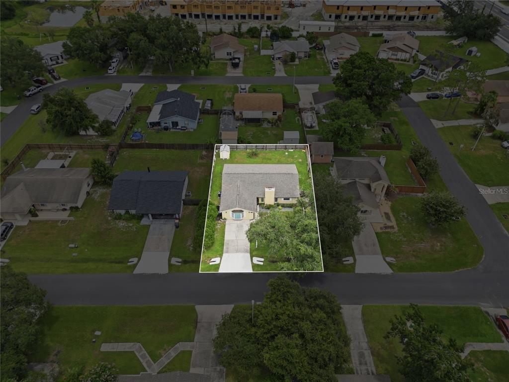 An aerial view shows a single-story house with a driveway and a fenced backyard — 4934 WILDFLOWER DRIVE, LAKELAND, FL