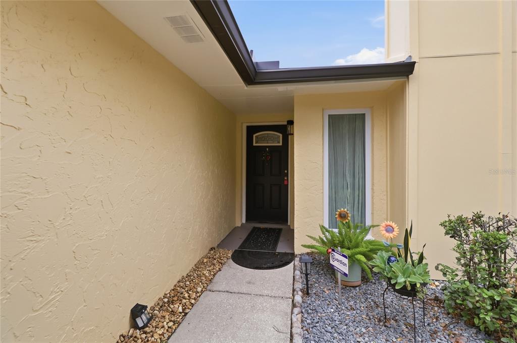 A concrete walkway leads to a black front door under a covered entryway — 4934 WILDFLOWER DRIVE, LAKELAND, FL