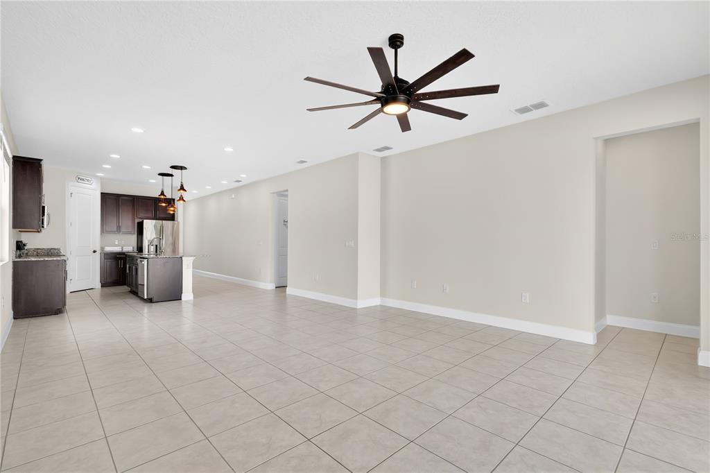 An open-concept kitchen and living area features tile flooring, dark cabinetry, and a ceiling fan — 5631 WESTERN SUN DRIVE, ST CLOUD, FL