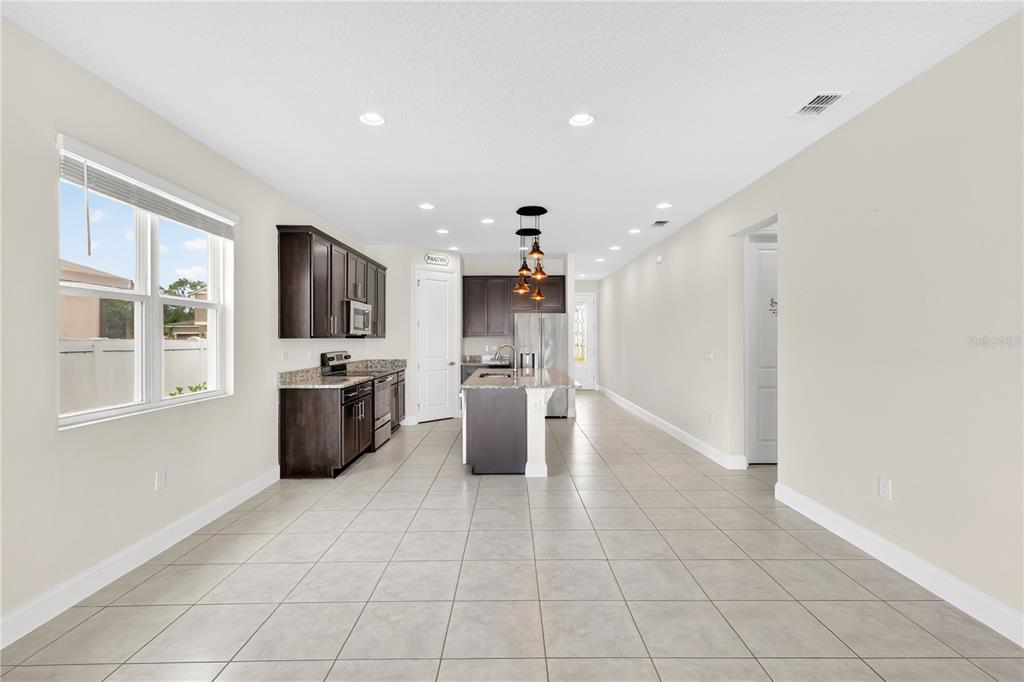 A kitchen features dark wood cabinets, granite countertops, a center island, and tile flooring — 5631 WESTERN SUN DRIVE, ST CLOUD, FL