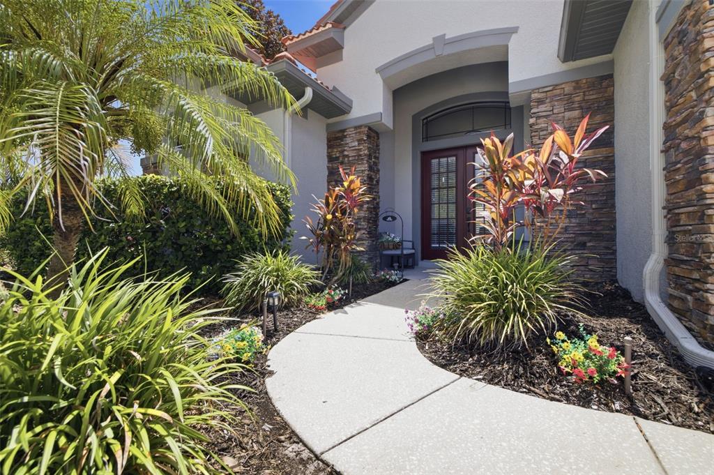 A concrete walkway leads to the front entrance of a house with stone veneer accents — 11508 OYSTER BAY CIRCLE, NEW PORT RICHEY, FL