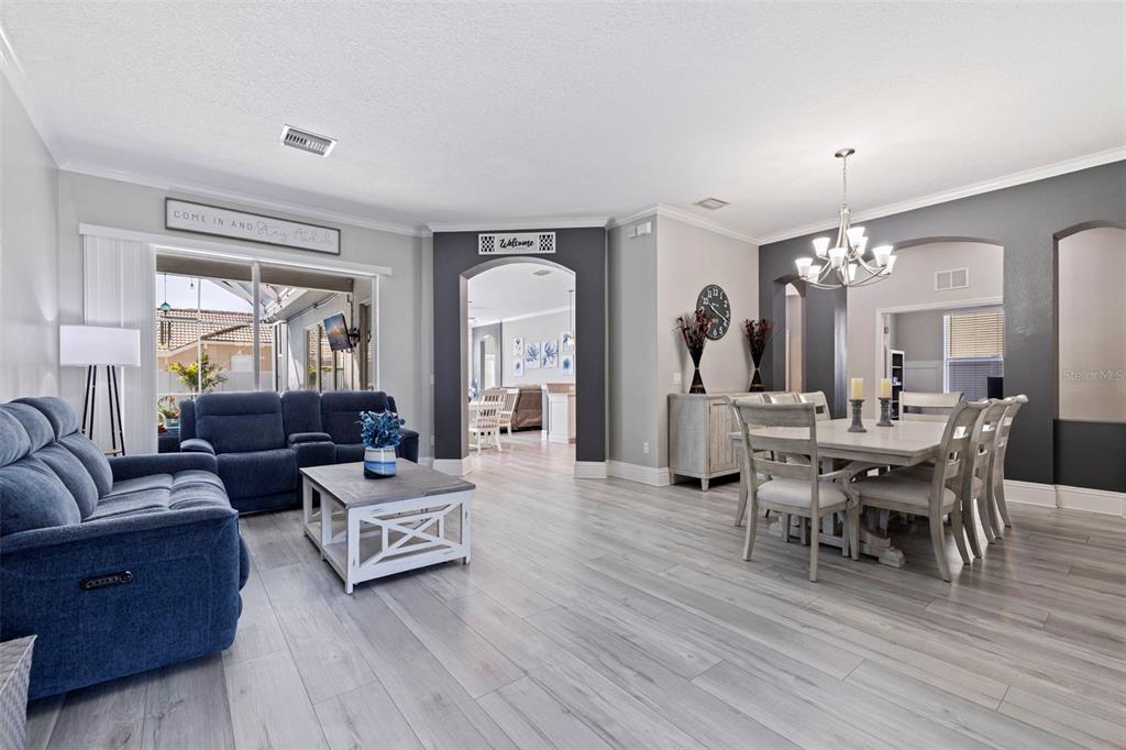 An open-concept living and dining area features light wood-look flooring and dark gray accent walls — 11508 OYSTER BAY CIRCLE, NEW PORT RICHEY, FL