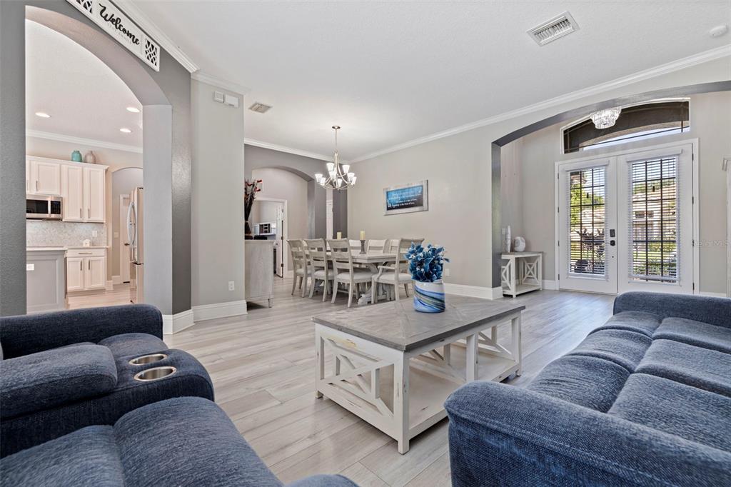 A living room with blue sofas and a coffee table opens to a dining area — 11508 OYSTER BAY CIRCLE, NEW PORT RICHEY, FL