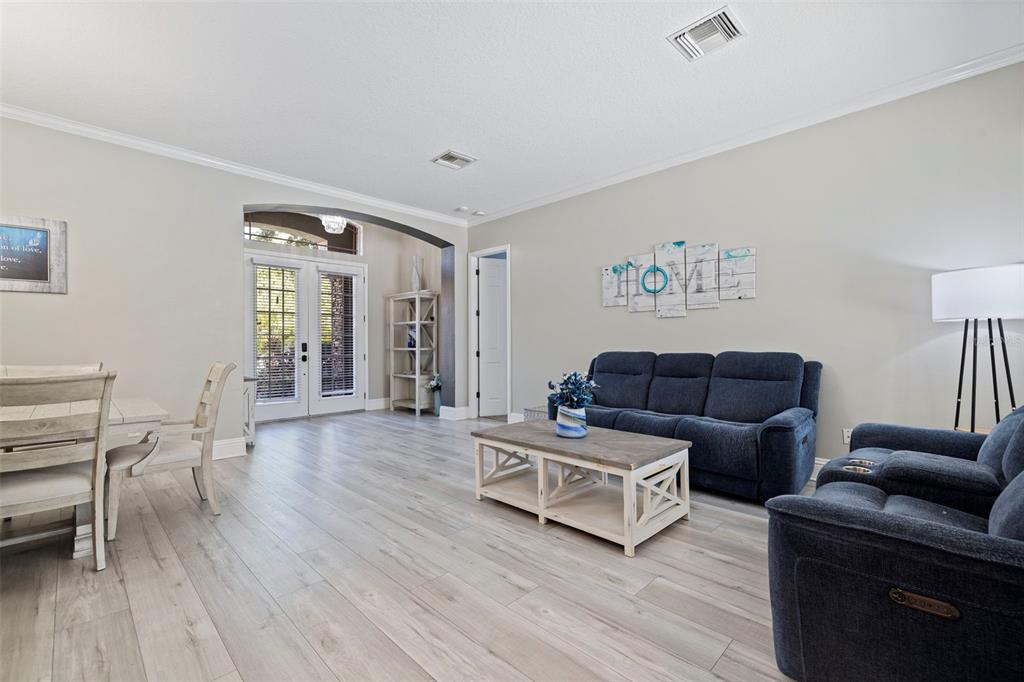 A living room and dining area with light wood-look flooring and blue fabric furniture — 11508 OYSTER BAY CIRCLE, NEW PORT RICHEY, FL