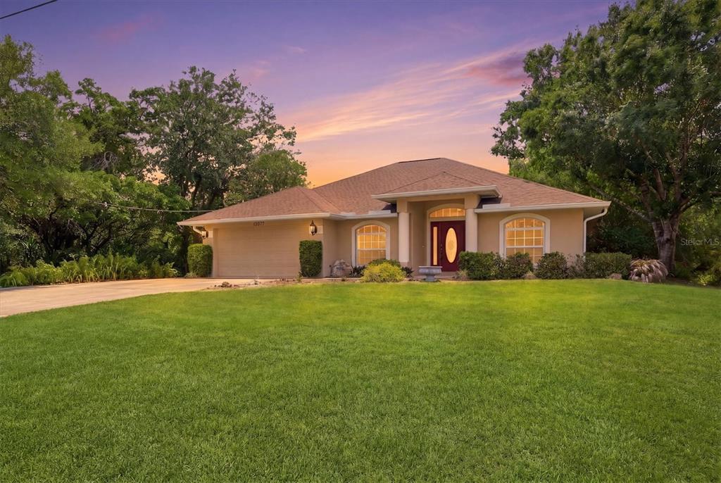 A single-story house with a tan exterior, a two-car garage, and a large front lawn — 12037 MALLORCA AVENUE, NORTH PORT, FL