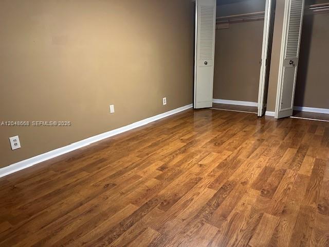 An empty room features wood-look flooring, tan walls, and a white louvered closet door — 5252 Bosque Ln # 9, West Palm Beach FL 33415, WEST PALM BEACH, FL