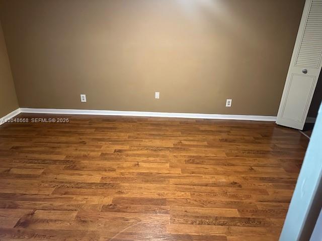 An empty room features brown walls, wood-look flooring, and a white louvered closet door — 5252 Bosque Ln # 9, West Palm Beach FL 33415, WEST PALM BEACH, FL