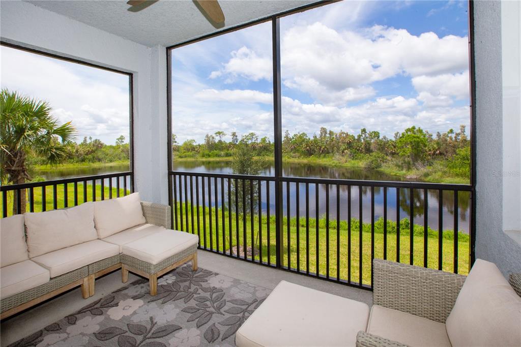 A screened-in patio with wicker furniture overlooks a grassy lawn and a pond — 14141 HERITAGE LANDING BOULEVARD UNIT 922, PUNTA GORDA, FL