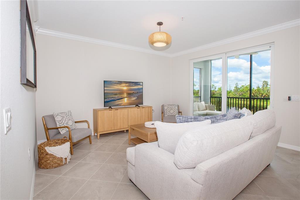 A living room features a light-colored sofa, a television on a wooden console, and tile flooring — 14141 HERITAGE LANDING BOULEVARD UNIT 922, PUNTA GORDA, FL